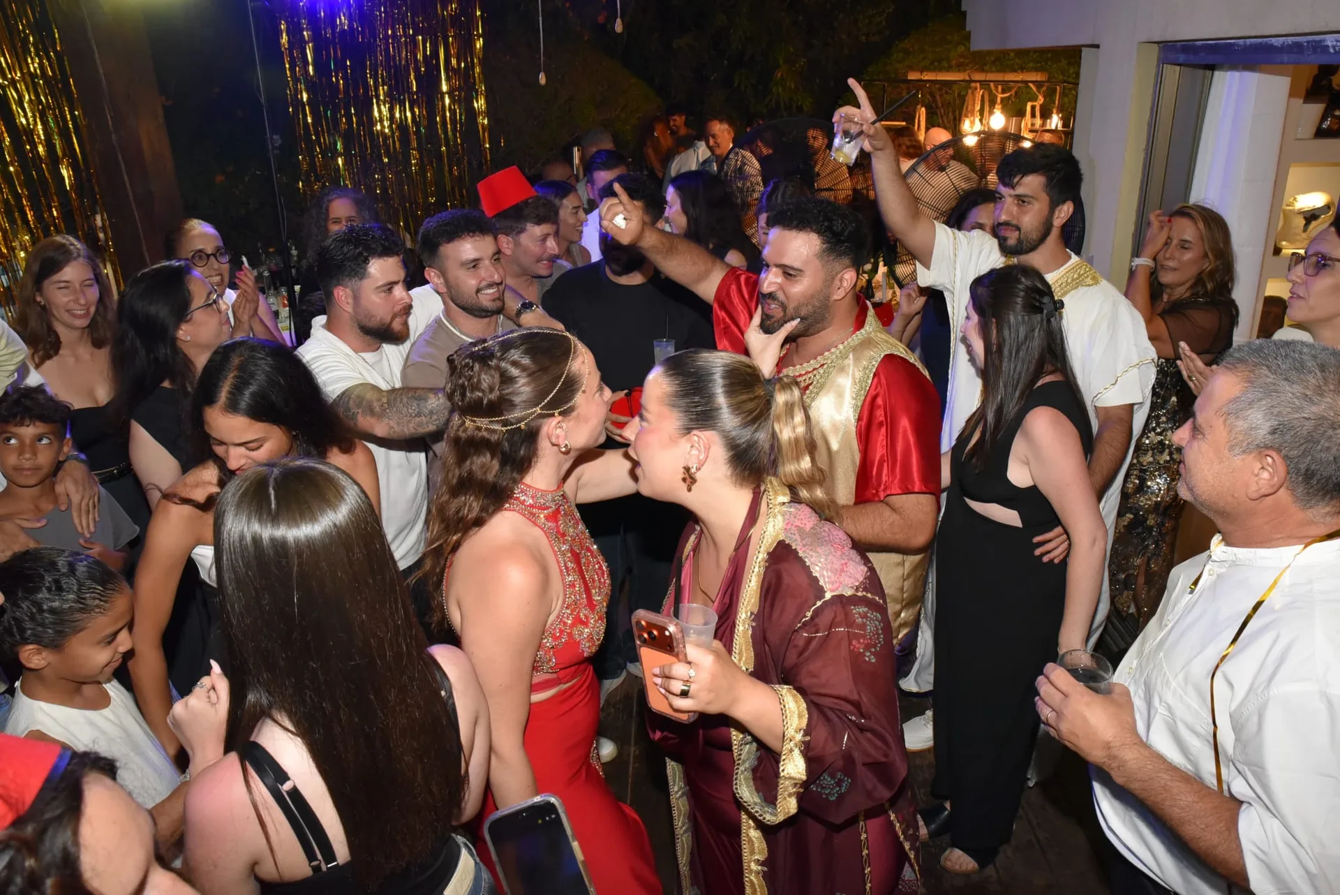 זוג ואורחים חוגגים בריקודי חינה בתלבושות מסורתיות